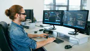 uno sviluppatore web che lavora con molti monitor e mette in atto tutto ciò che ha appreso tramite il corso professionale frequentato