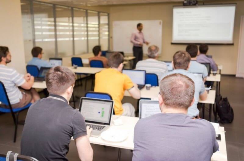 Corsisti che assistono ad un corso professionale per intraprendere nuovi percorsi lavorativi divisi per banchi e ognuno col proprio pc